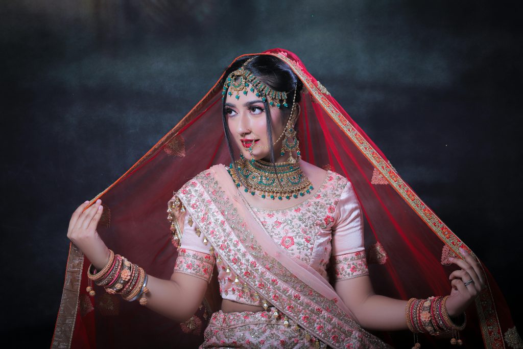 Beautiful Indian bride posing in traditional attire, showcasing intricate jewelry and a saree.